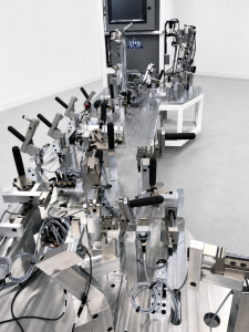 Industrial lab rig with numerous metallic levers and cables on a stainless workbench in a white room