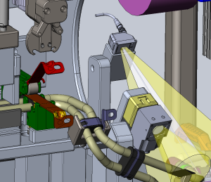 Interior of an industrial machine with a laser head emitting two yellow beams toward a component, surrounded by cables and metal brackets.